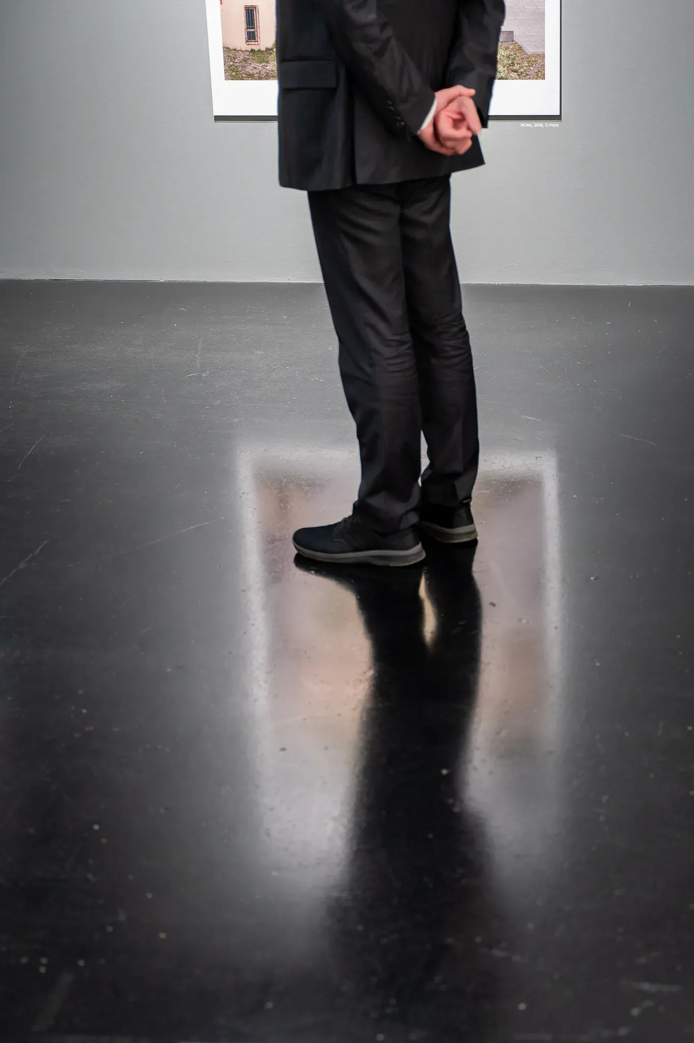 Ausstellungsraum, Person im Anzug vor einer gerahmten Arbeit.